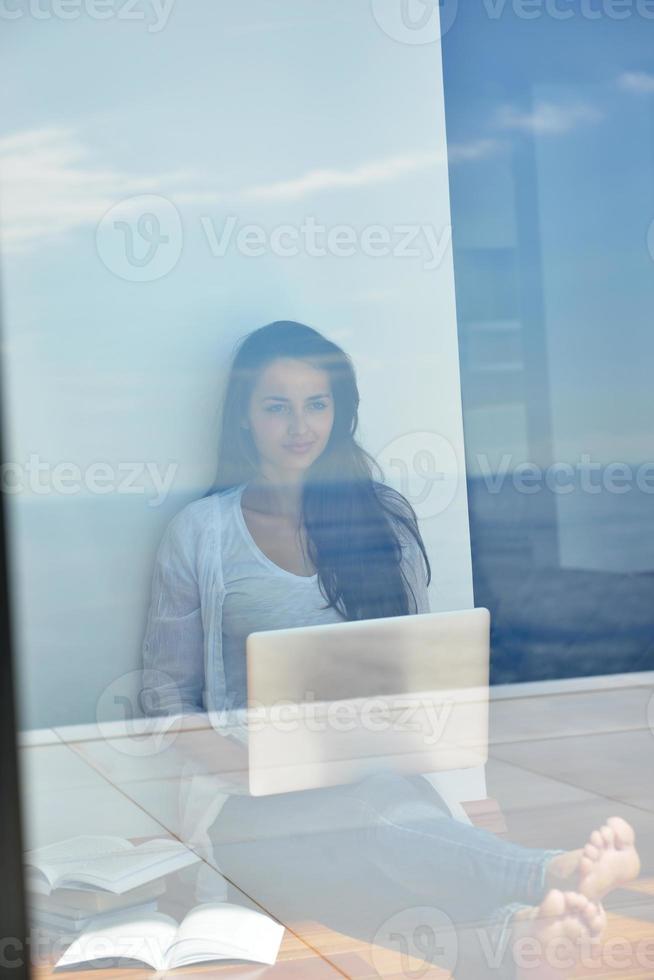 relaxed young woman at home working on laptop computer photo
