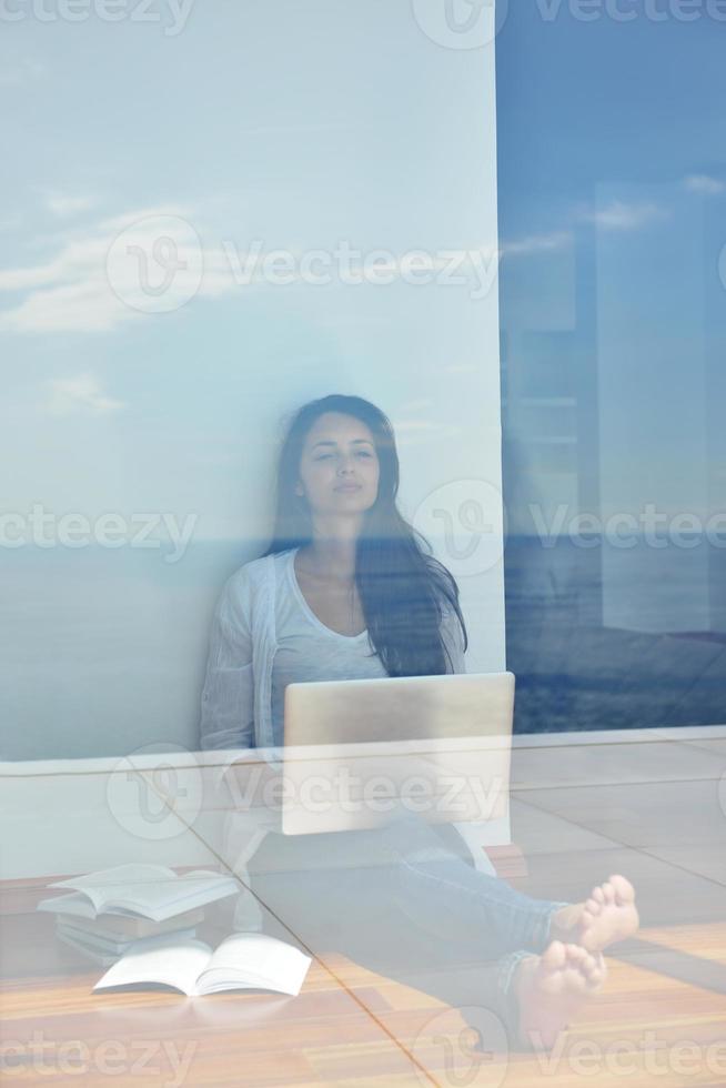 relaxed young woman at home working on laptop computer photo
