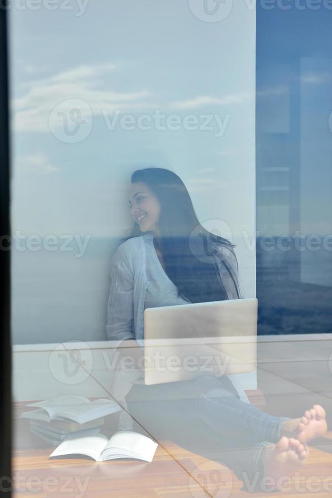 relaxed young woman at home working on laptop computer photo