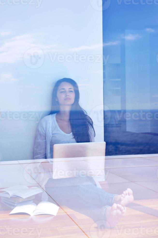 relaxed young woman at home working on laptop computer photo