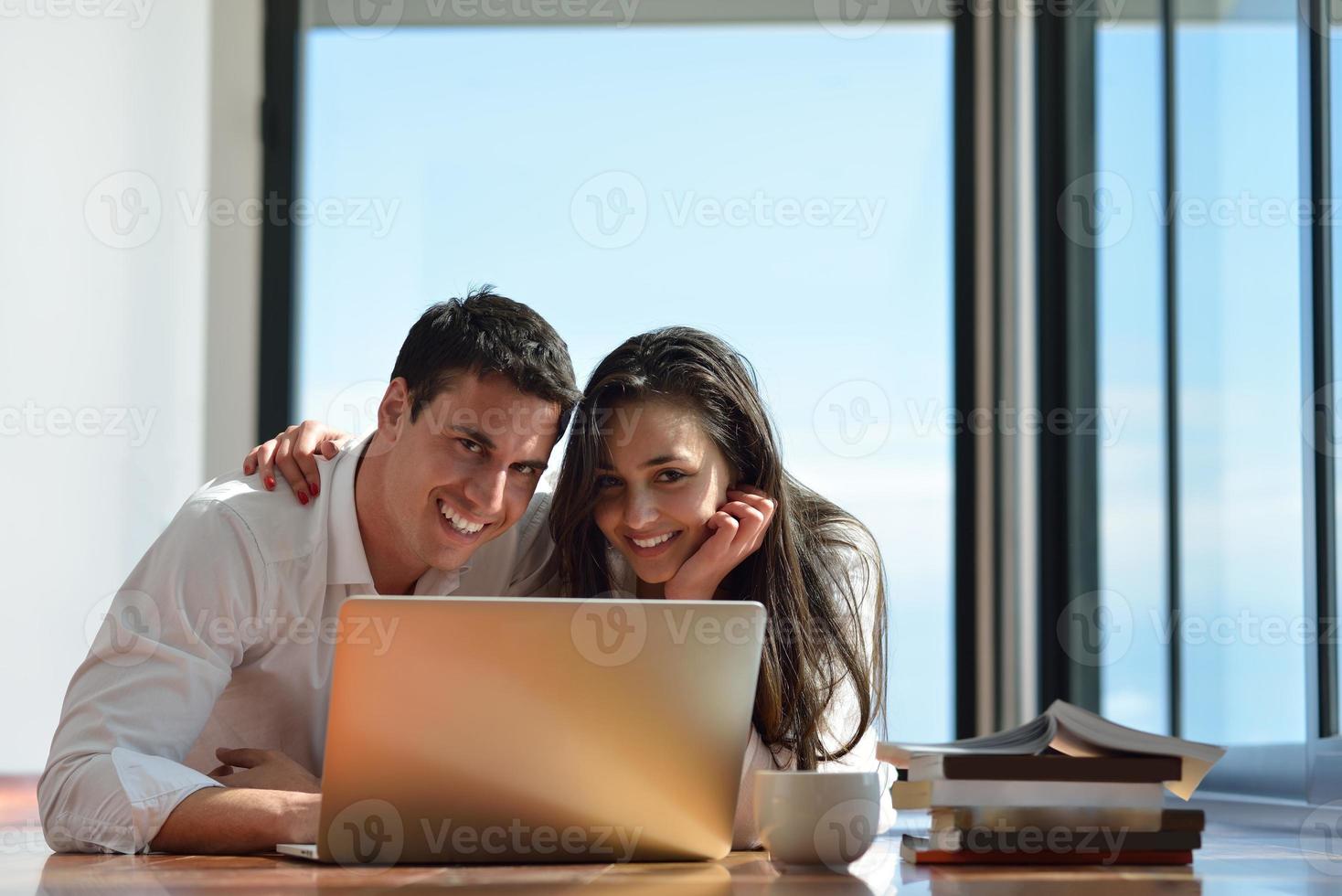 relaxed young couple working on laptop computer at home photo