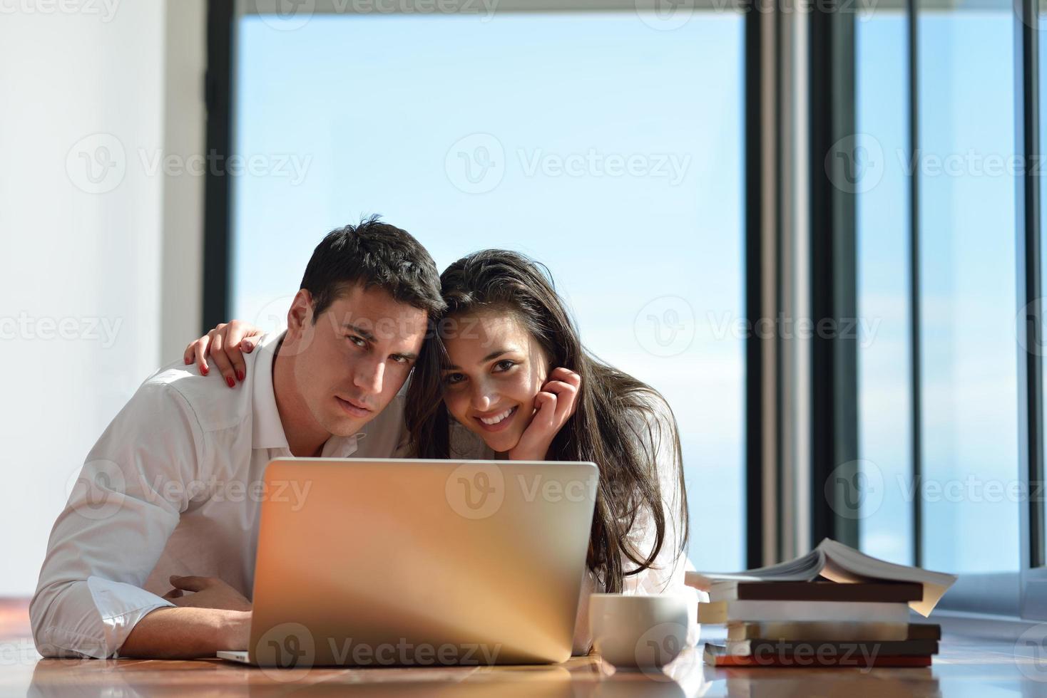 relaxed young couple working on laptop computer at home photo