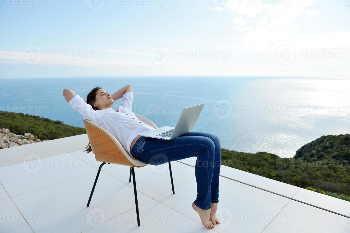 relaxed young woman at home working on laptop photo