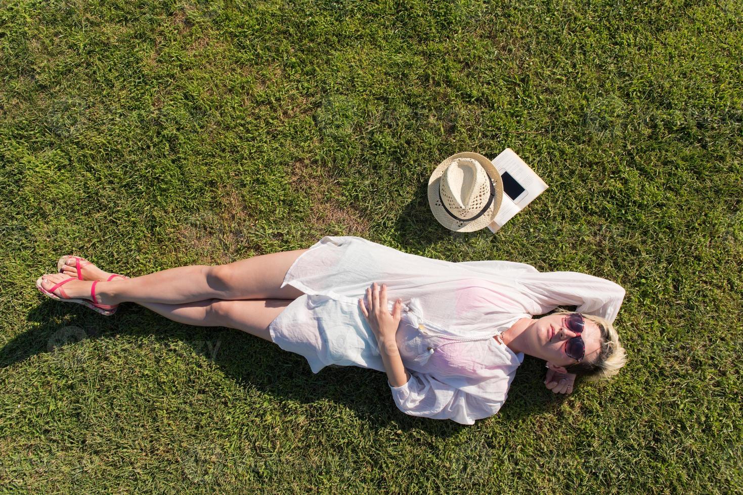 Top view from above of a woman lying and relaxing on a meadow covered with green grass on a sunny summer or spring day. photo