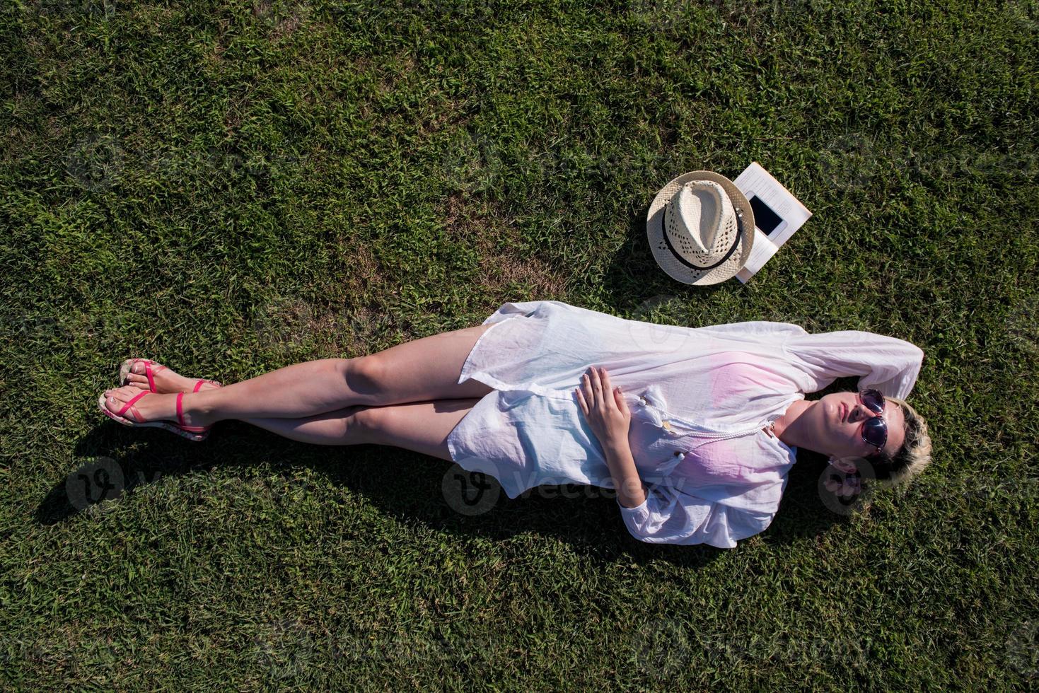 Top view from above of a woman lying and relaxing on a meadow covered with green grass on a sunny summer or spring day. photo