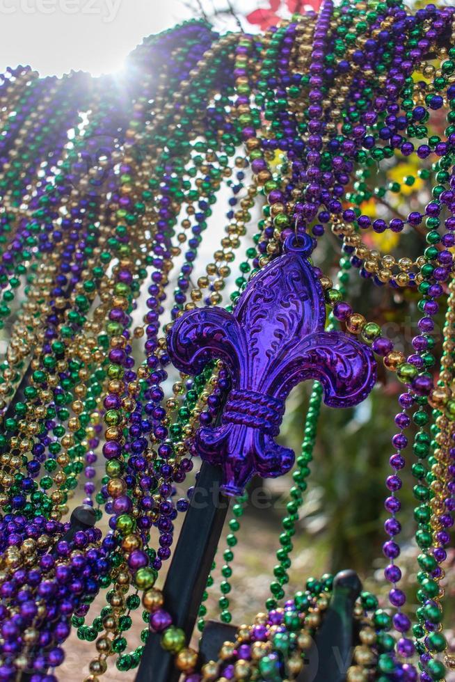 Mardi Gras beads covering wrought iron fence with fleur de lis photo