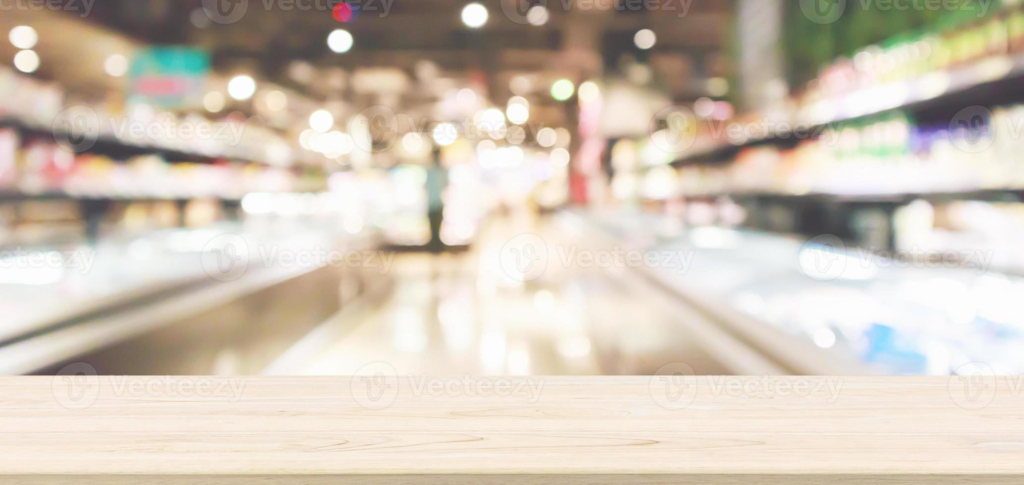 Wood table top with Abstract supermarket grocery store refrigerator blurred defocused background with bokeh light photo