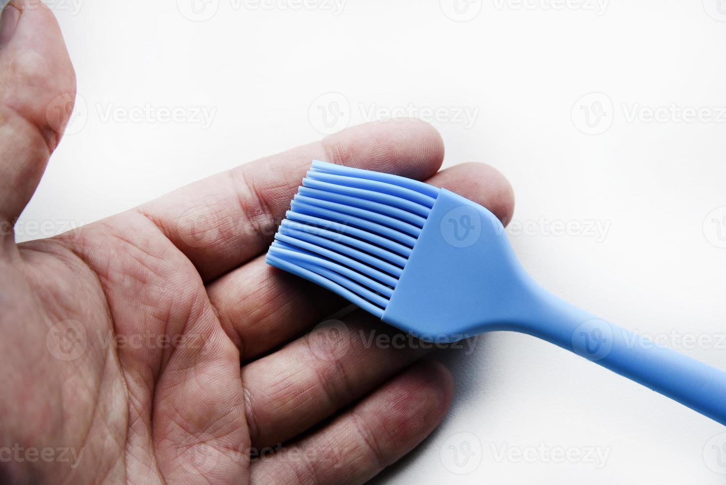 Blue plastic brush for smearing sunflower oil on a frying pan. A device for smearing oil. photo