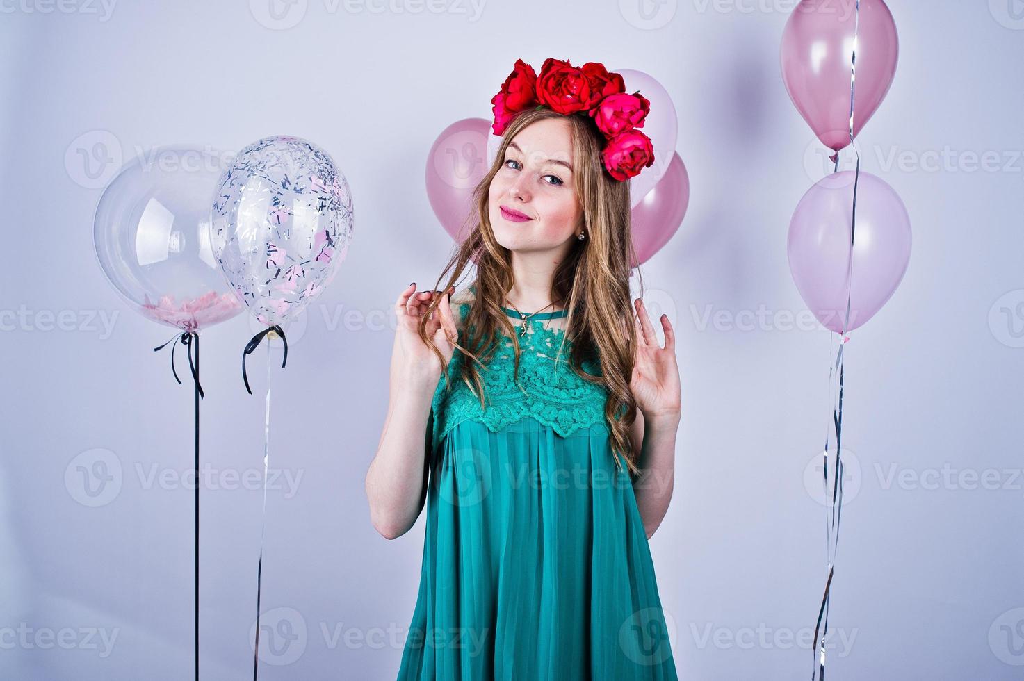 Happy girl in green turqoise dress and wreath with colored balloons isolated on white. Celebrating birthday theme. photo