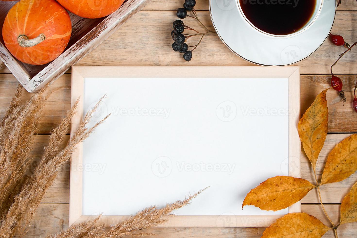 Autumn flat lay. Cup of hot espresso coffee and fallen yellow leaves on wooden background. Empty frame mock up for text. Morning concept. photo