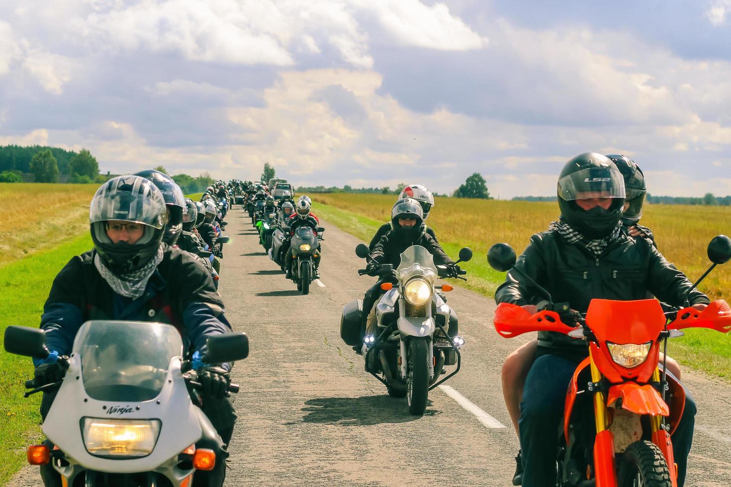 Group of motorcyclists rides on asphalt country road on summer sunny day. Parade of motorcycles. photo