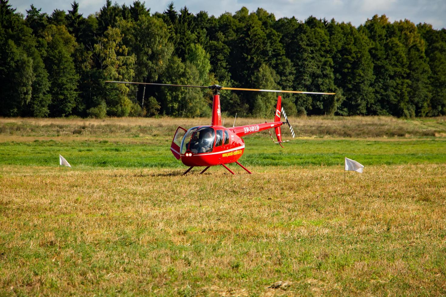 Private pleasure red helicopter on the takeoff site in the field. photo