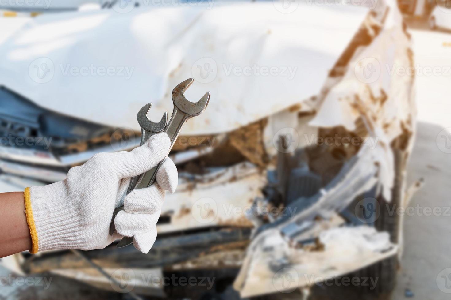 hand hold wrench with car crash damage background photo