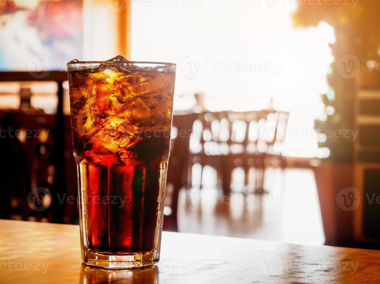 Cola glass with ice on wood table in restaurant background photo