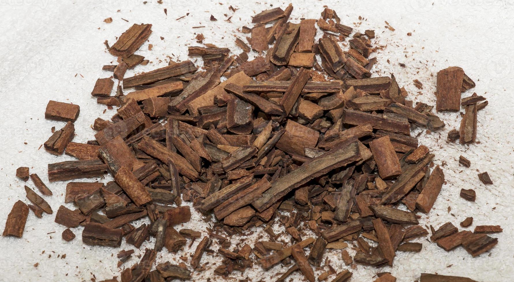 Cinnamon sticks are crushed into small pieces for making a tea mixture. A pile of cinnamon on a white cloth. photo