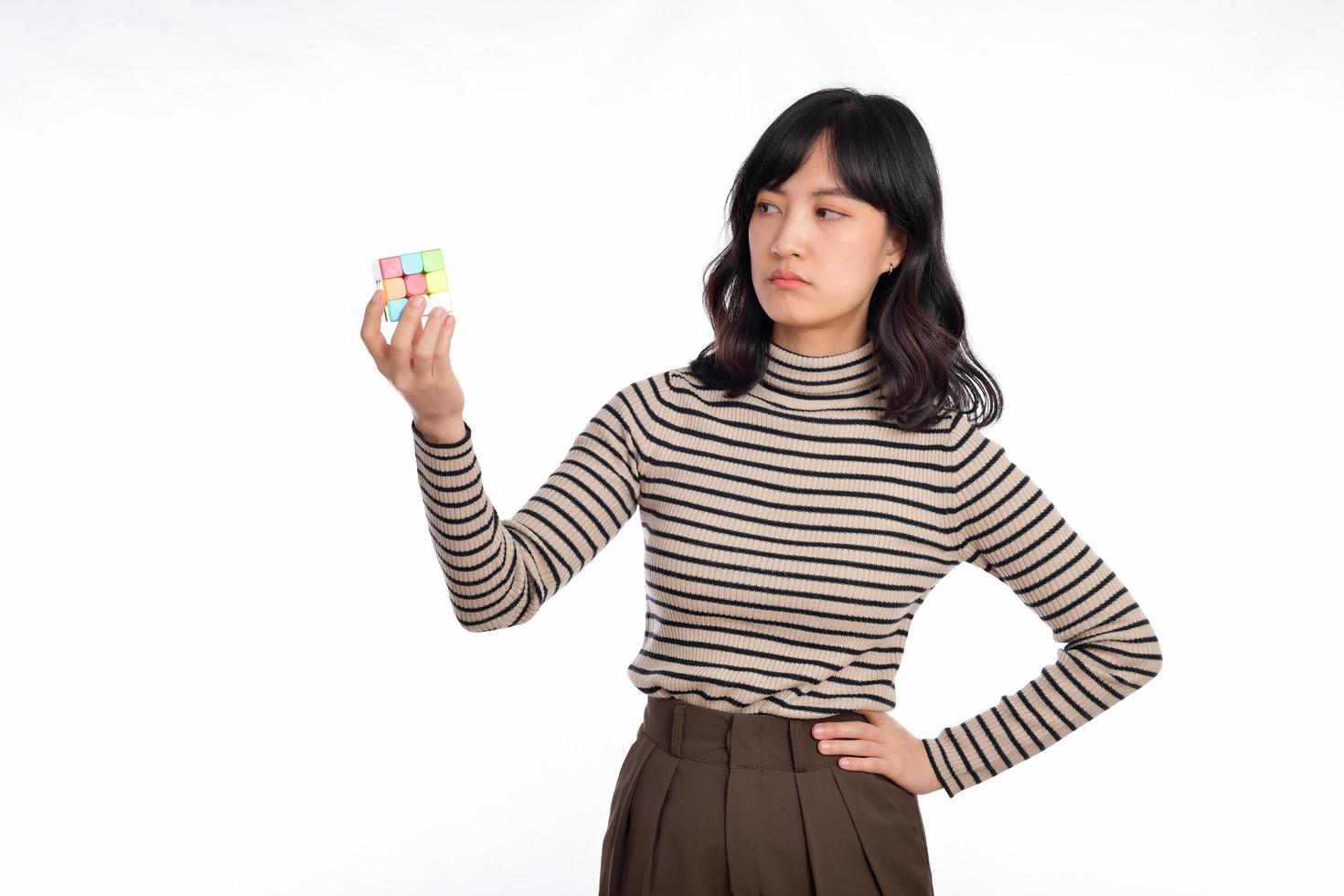 Asian woman holding a rubik cube standing on white background. solving cubic problems, problem solution and making strategic moves concept photo