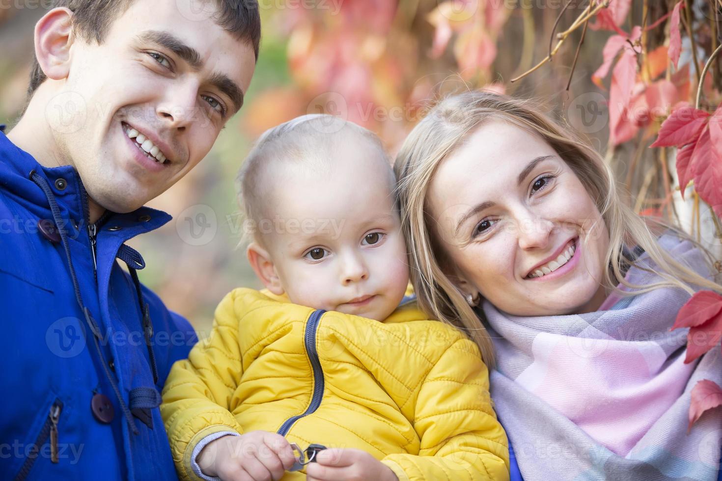 contento familia mamá papá y pequeño hijo Mira a el cámara y sonrisa. foto