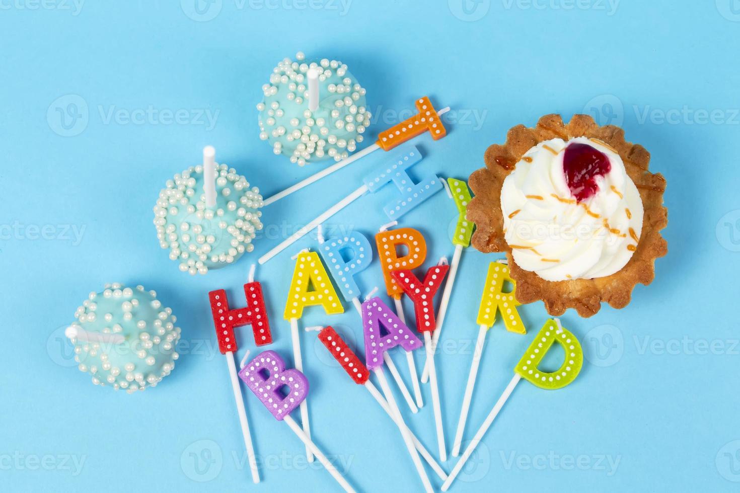 Cakes and cupcakes with rainbow-colored birthday candles with the words Happy Birthday. Anniversary celebration. photo