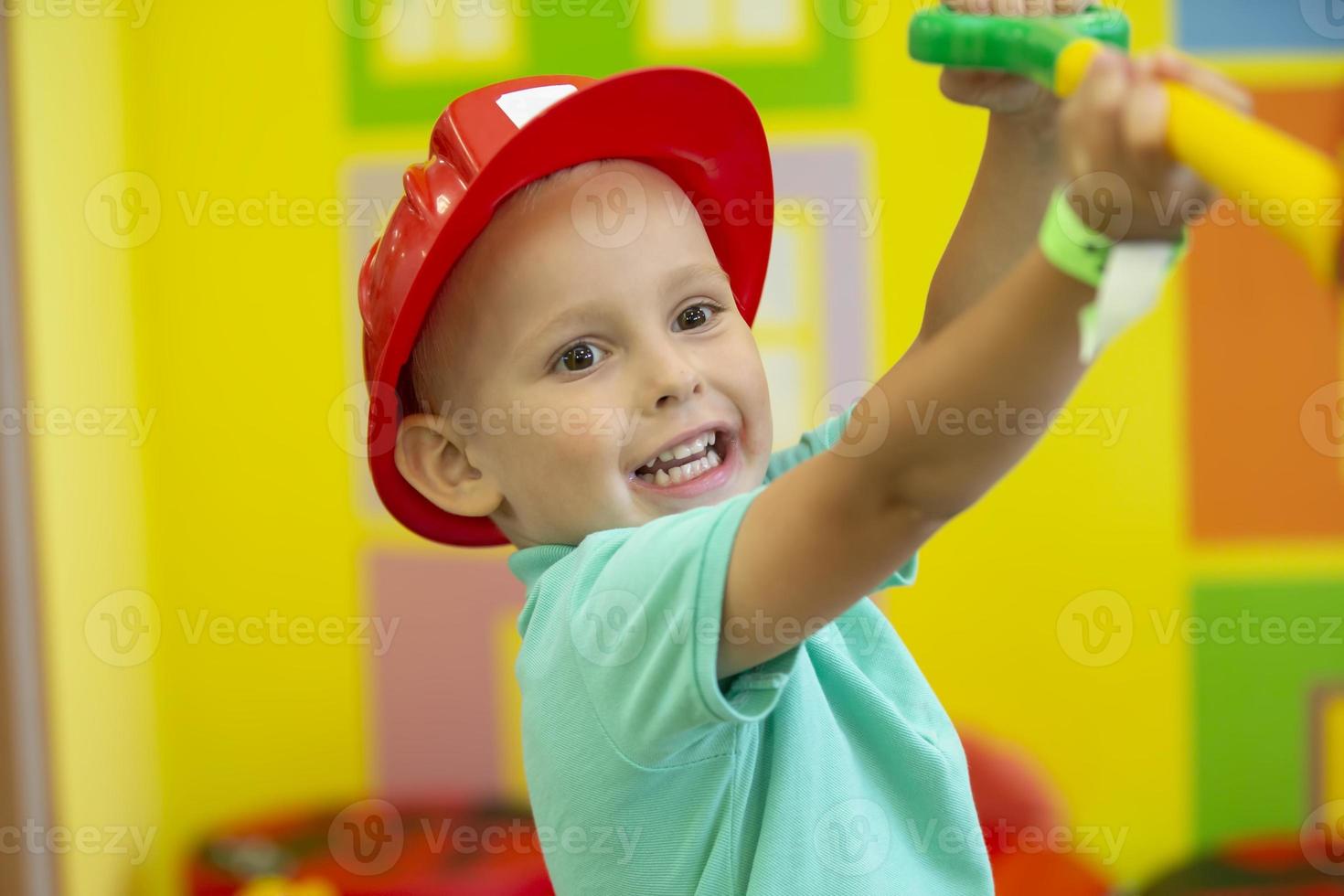 un pequeño chico en un protector casco obras de teatro un constructor. foto