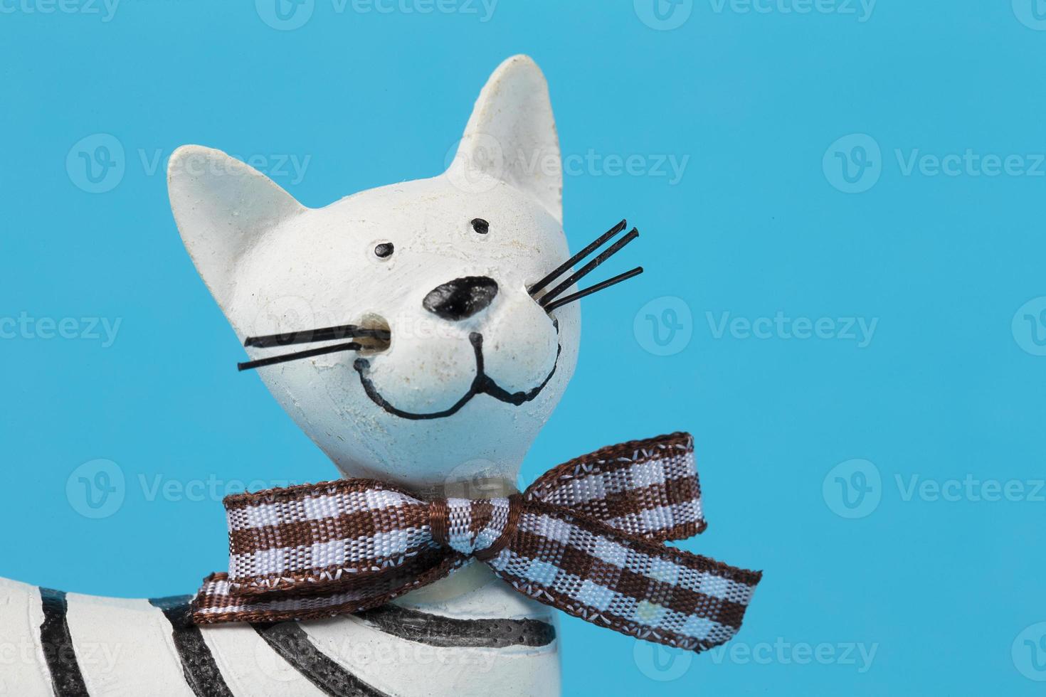 Funny toy clay cat with a bow on a blue background. photo
