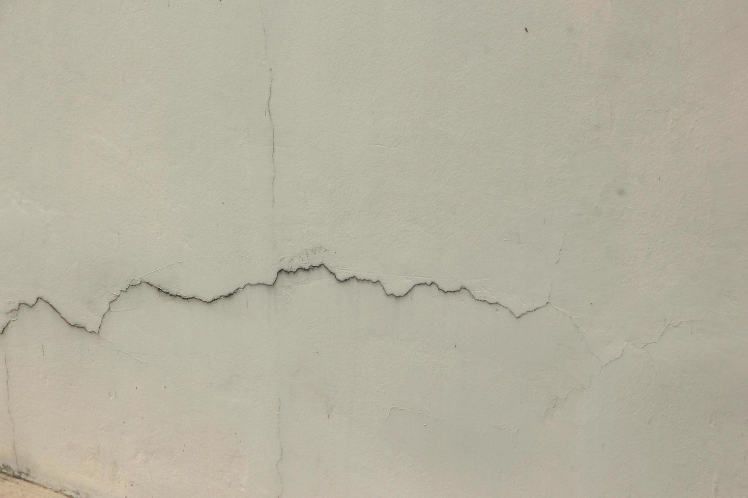 Damaged cement wall with wall cracks in urban area. photo