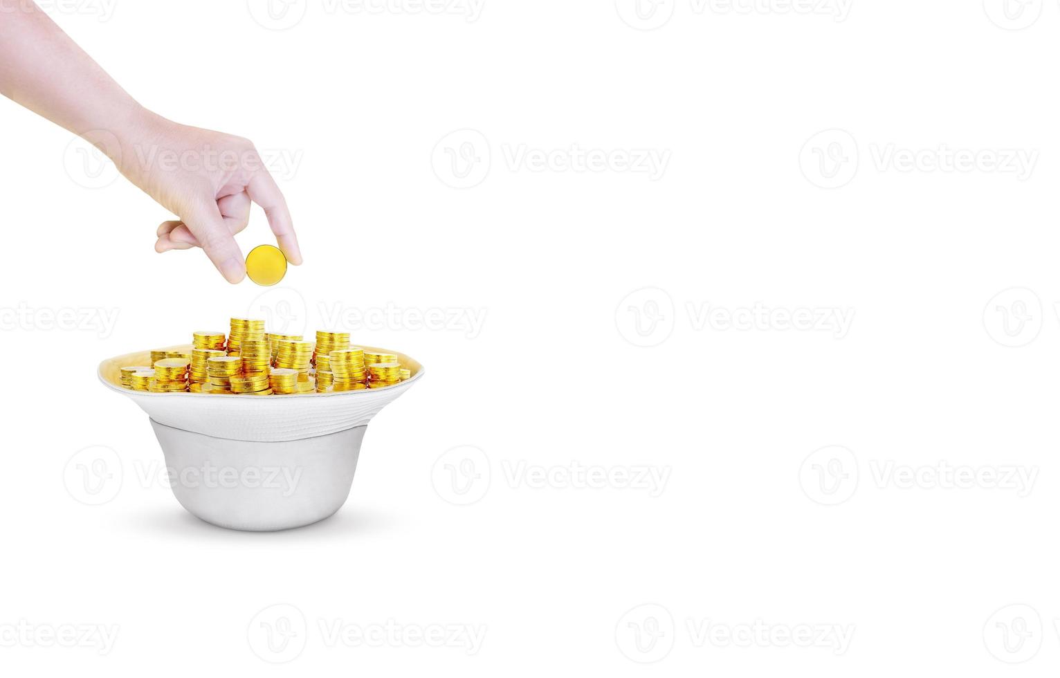 Hand is dropping gold coins in white bucket hat on white background. photo