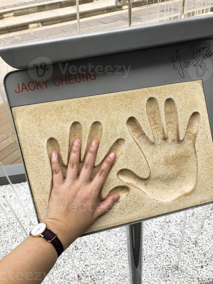 Tourist put his hand at the Hong Kong Chinese actor Jacky Cheung and celebrity hand prints memorial signature at the Avenue of Stars in Hong Kong. photo