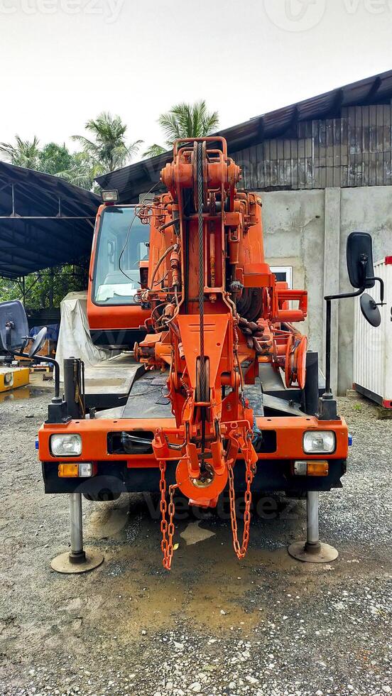 Front view of orange small city crane or CTC jacking up and parking. photo