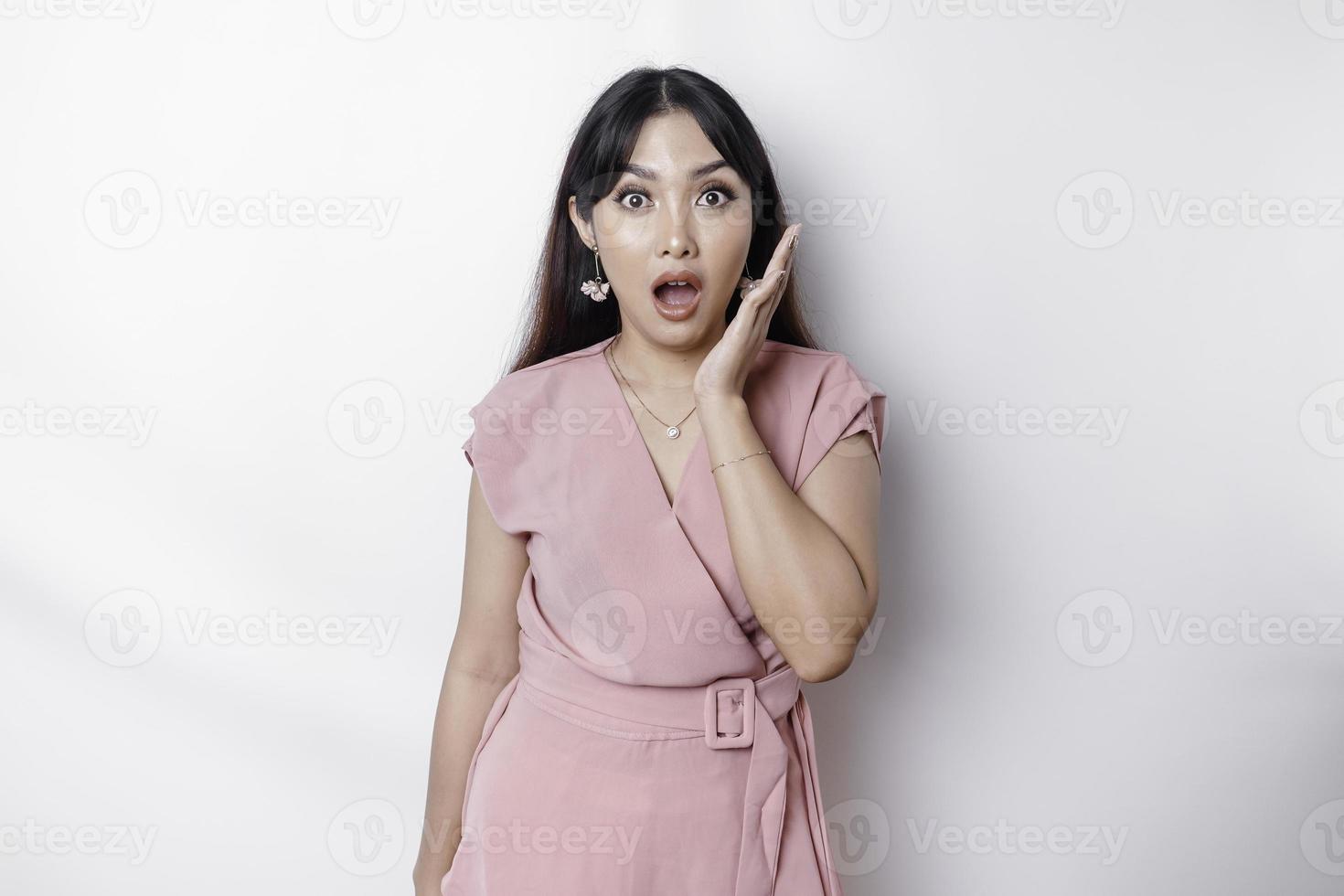 sorprendido joven asiático mujer cubierta boca con manos y curioso a cámara mientras en pie en contra blanco antecedentes foto