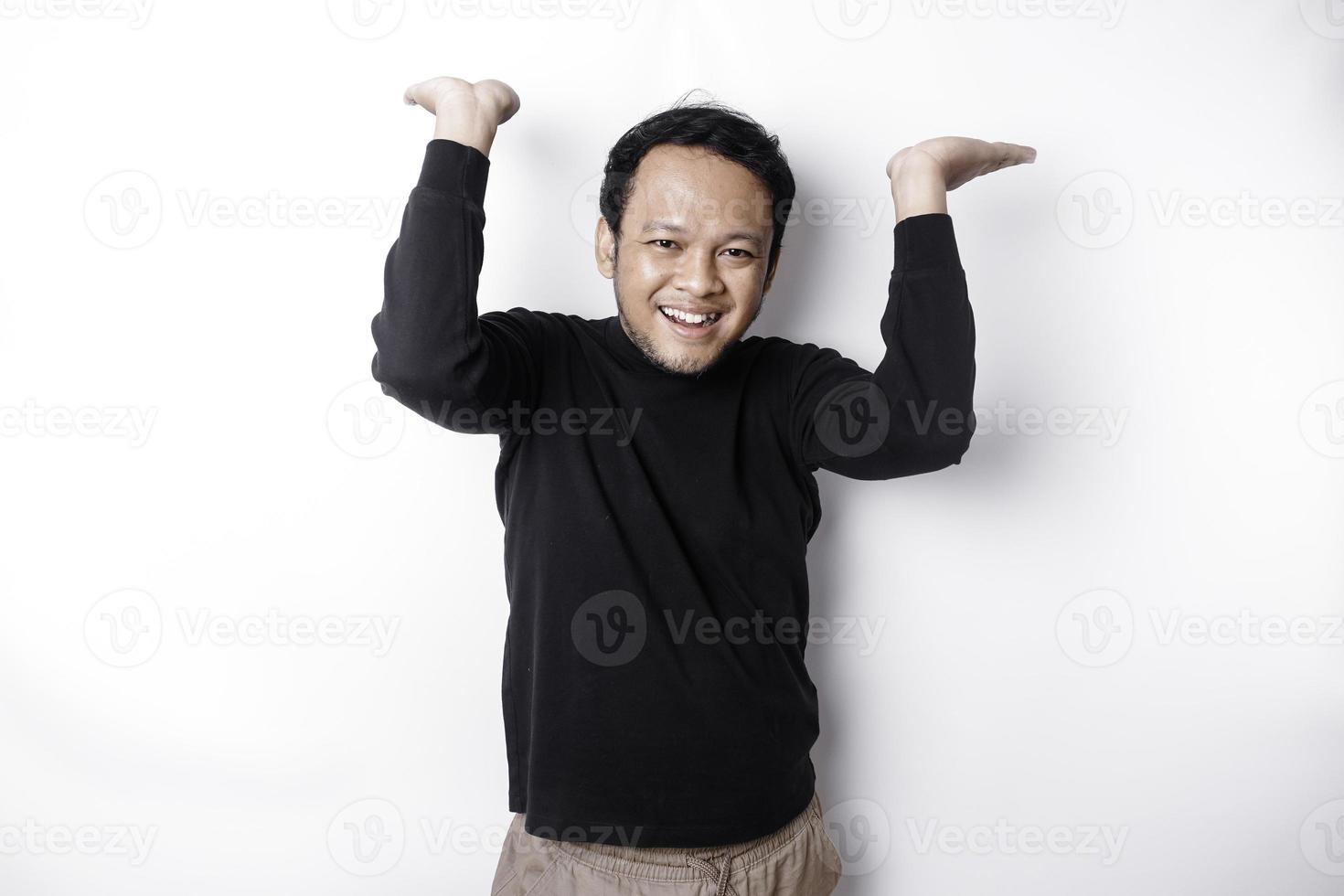 Excited Asian man wearing black shirt pointing at the copy space on top of him, isolated by white background photo