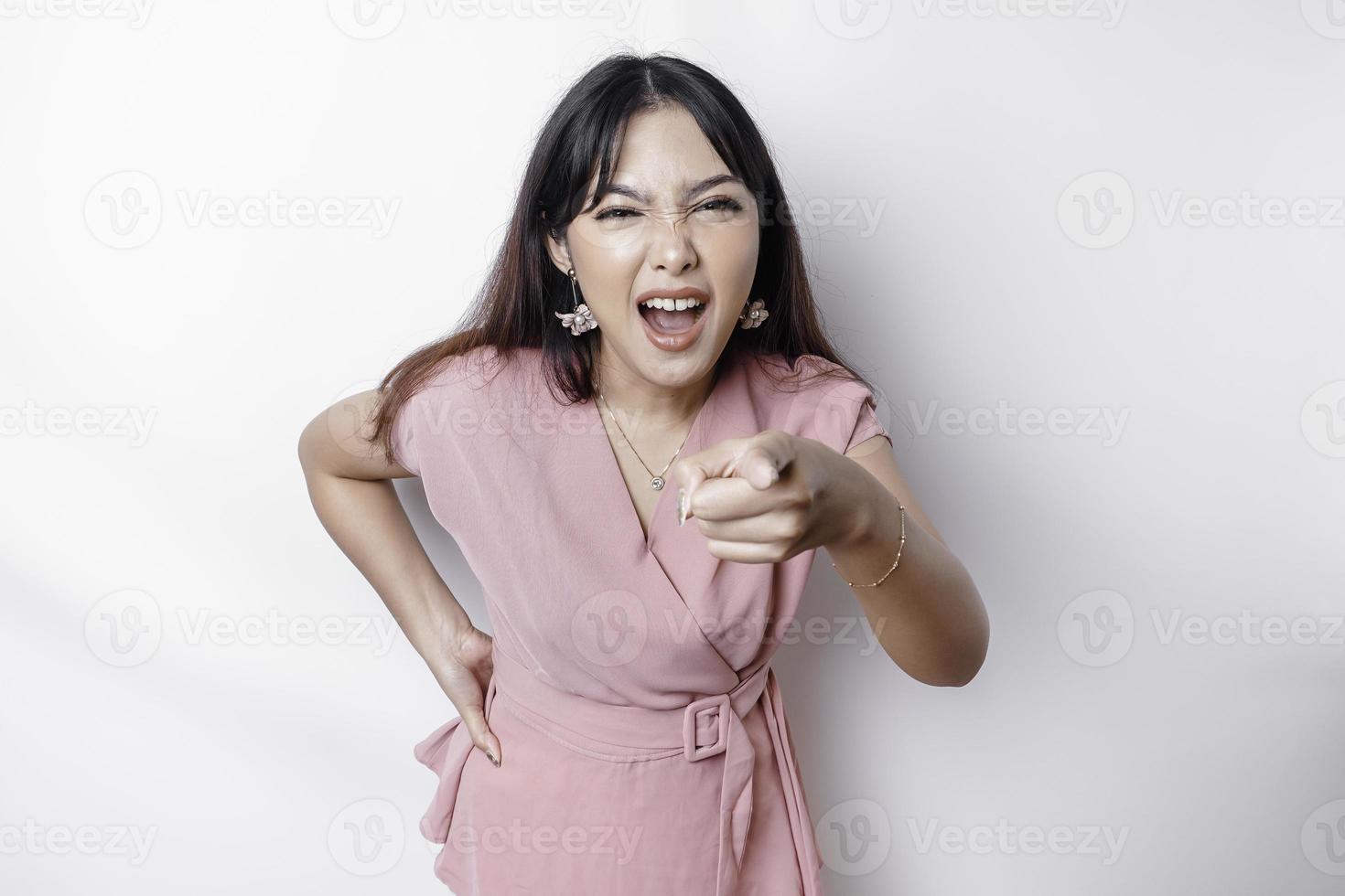 A dissatisfied young Asian woman looks at the camera posing on a white background, disgruntled girl with irritated face expressions show negative attitude concept image photo