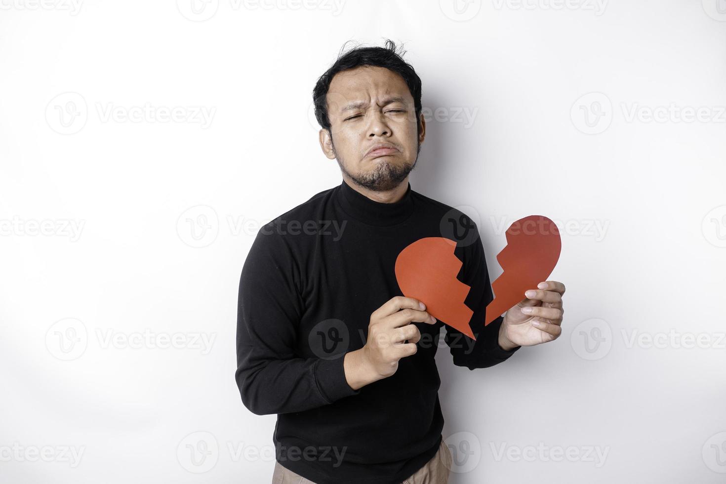 Beautiful young Asian man expressed his sadness while holding broken heart isolated on white background photo