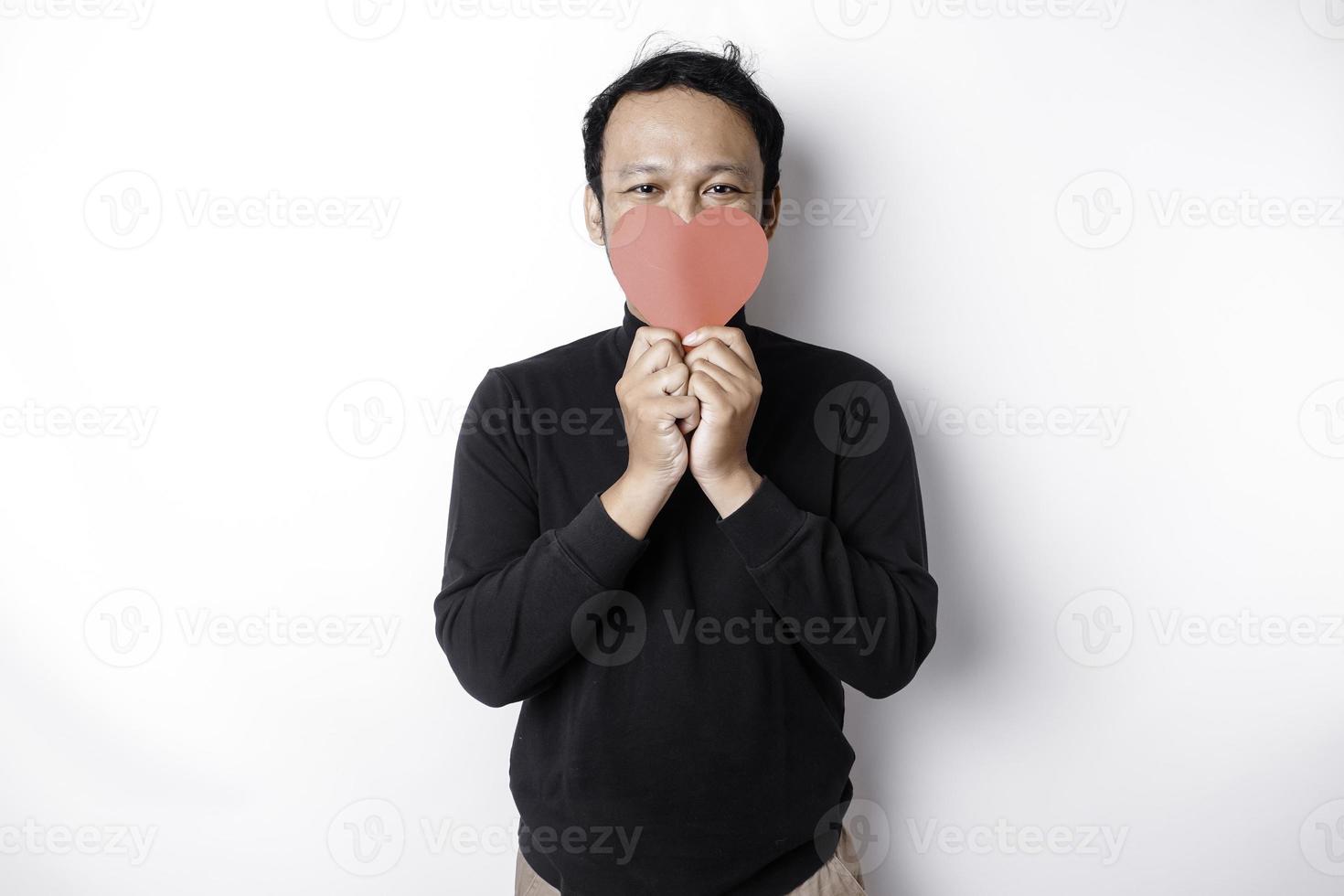 asiático hombre participación un rojo papel corazón forma cubierta su rostro. enamorado concepto foto