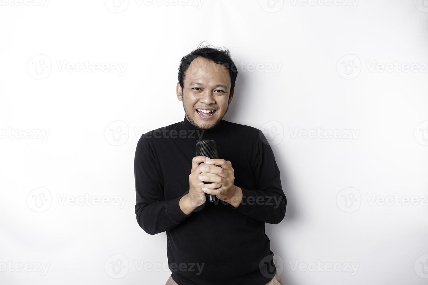 retrato de un hombre asiático despreocupado, divirtiéndose en el karaoke, cantando en el micrófono mientras está de pie sobre fondo blanco foto