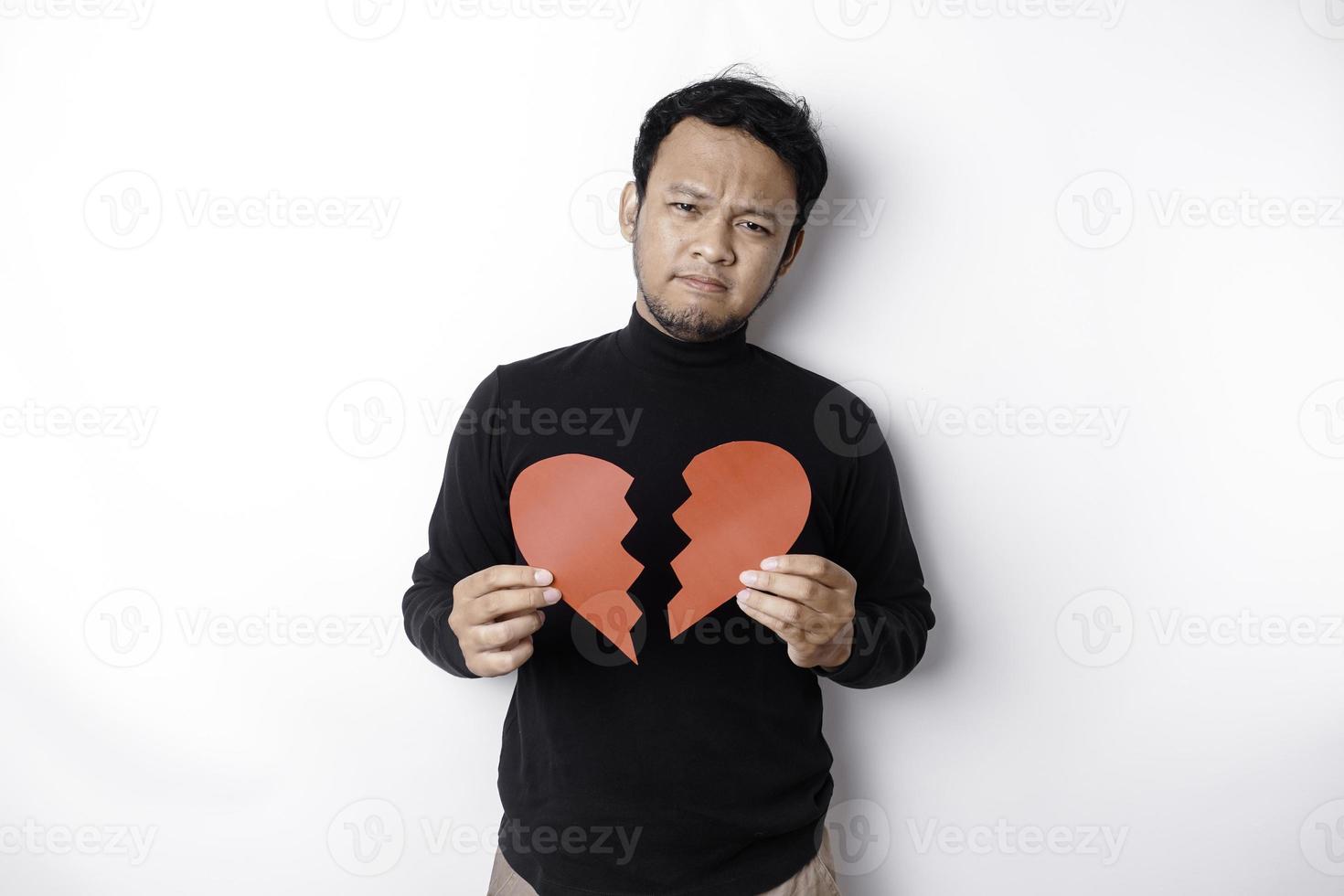 Beautiful young Asian man expressed his sadness while holding broken heart isolated on white background photo