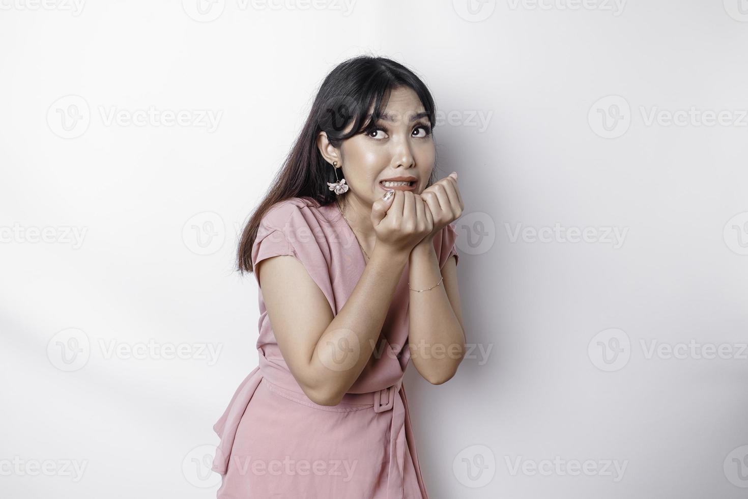 Young Asian woman isolated on white background, looks depressed, face covered by fingers frightened and nervous. photo