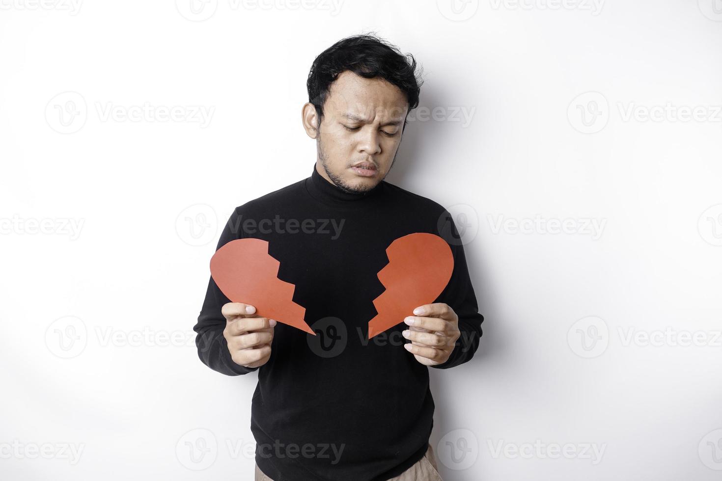 Beautiful young Asian man expressed his sadness while holding broken heart isolated on white background photo