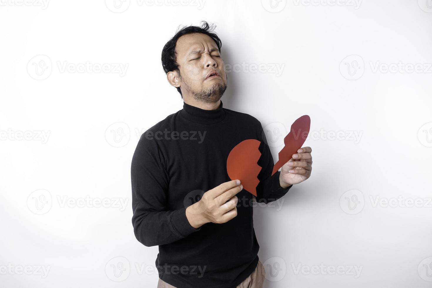 Beautiful young Asian man expressed his sadness while holding broken heart isolated on white background photo