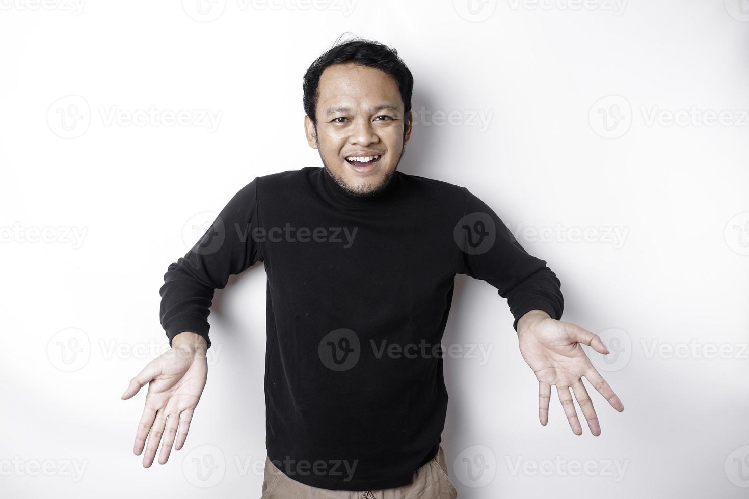 emocionado asiático hombre vistiendo negro camisa señalando a el Copiar espacio abajo a él, aislado por blanco antecedentes foto