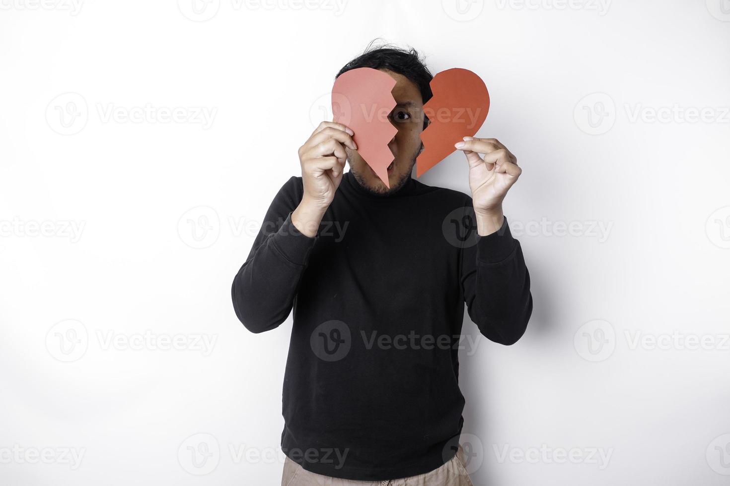 Beautiful young Asian man expressed his sadness while holding broken heart isolated on white background photo