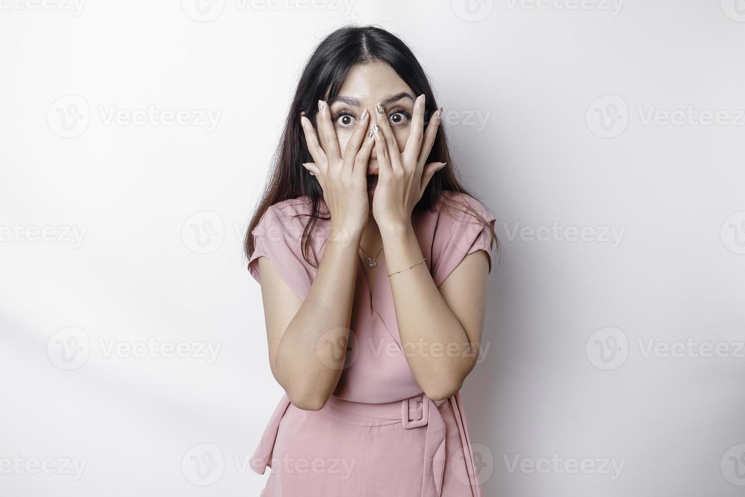 Funny obvious peeking Asian woman in pink blouse isolated on white background. photo