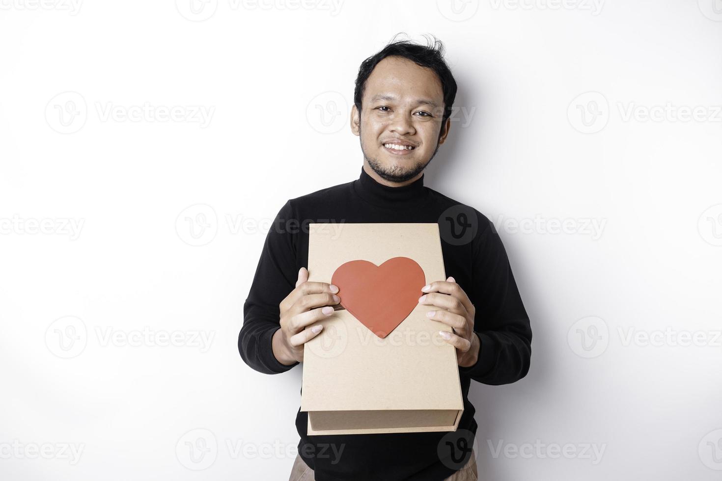 Beautiful young Asian man wearing black shirt holding gift box red heart, Valentine's Day concept. photo