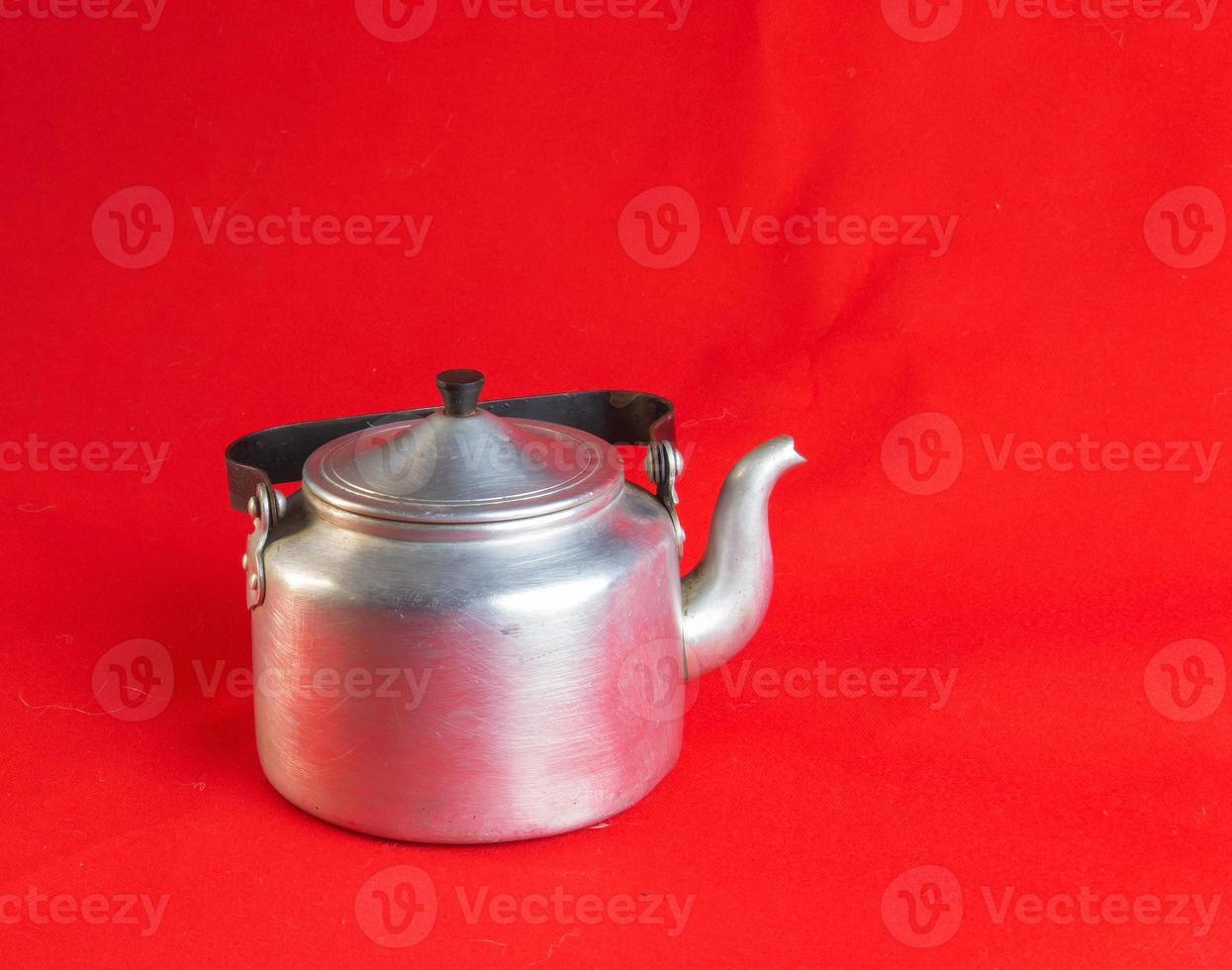 Old soldier's aluminum teapot from the Second World War on a red background. photo