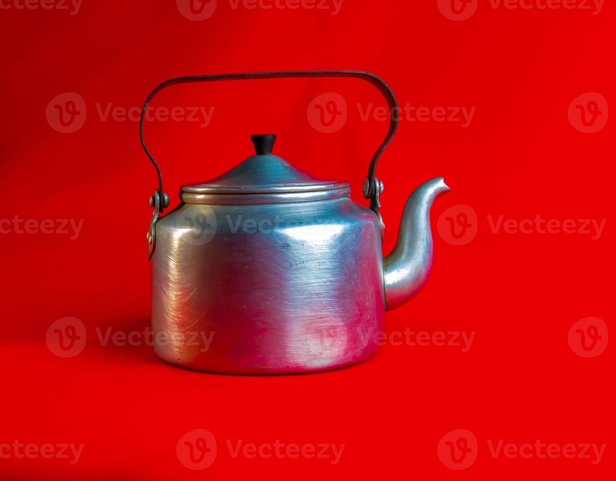 Old soldier's aluminum teapot from the Second World War on a red background. photo