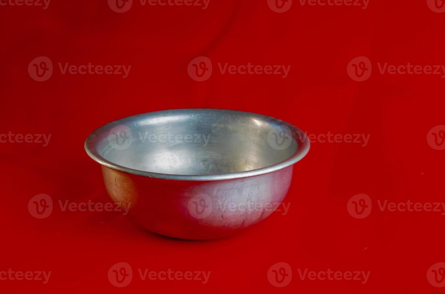 An old aluminum bowl made in circa 1960 against a red background. photo