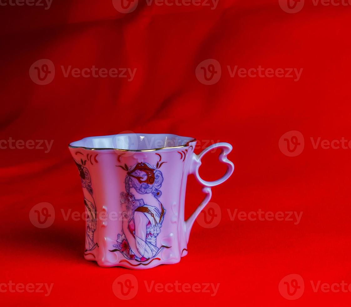 porcelana rosado taza de un raro forma es hecho en el checo república. un taza con un romántico modelo en un rojo antecedentes. foto