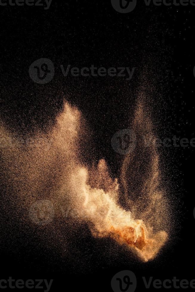 Brown color sand splash against black background. Sand fly wave in the air. photo