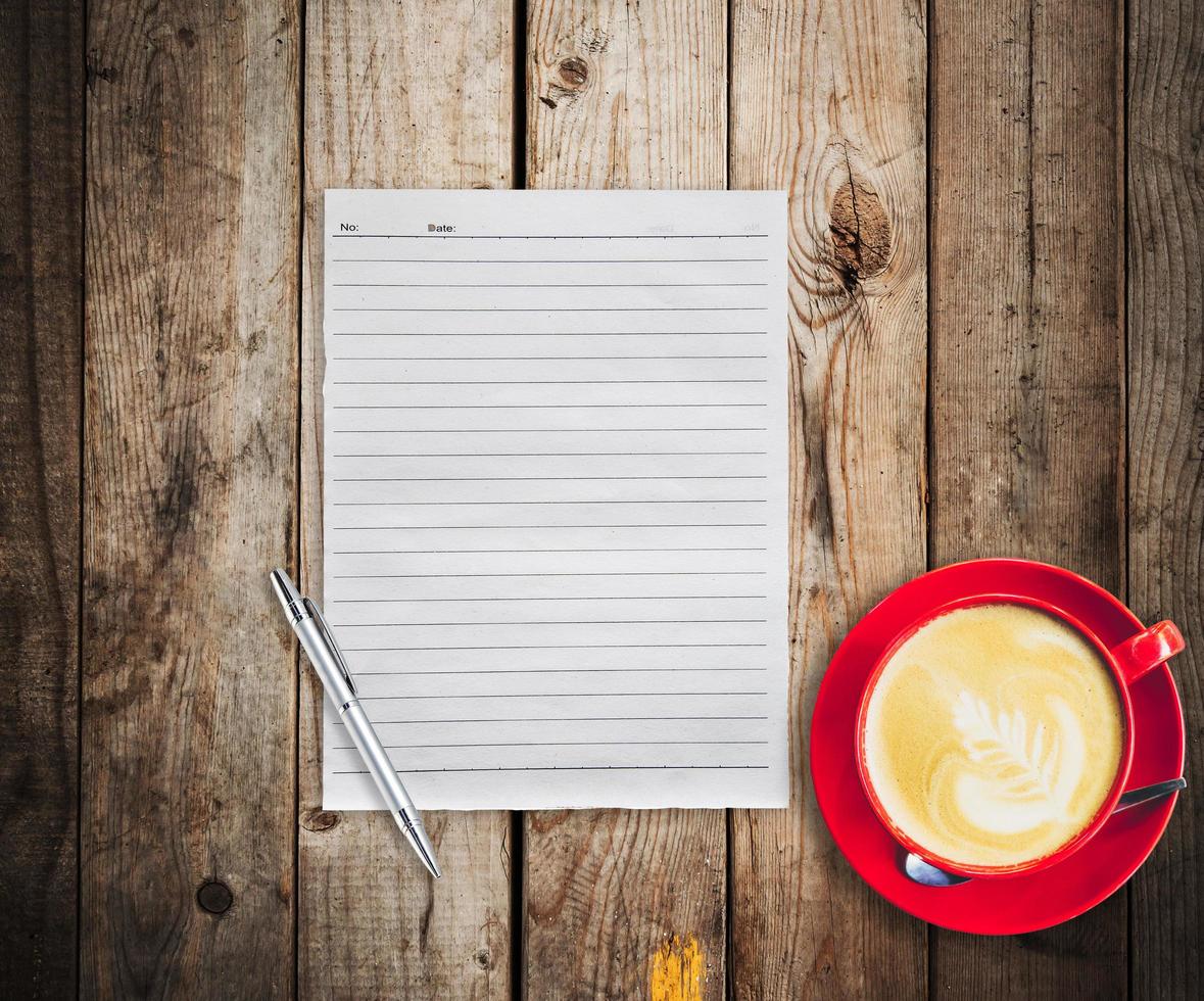 Empty paper and pen with red cup coffee on wood table background photo