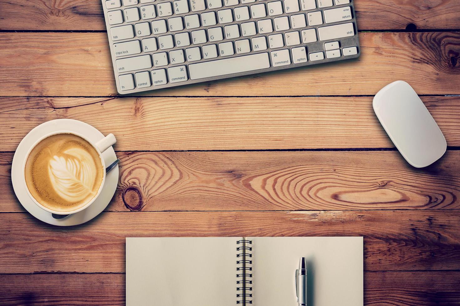 Office table with computer, notebook and coffee cup. View from above for vintage tone. photo
