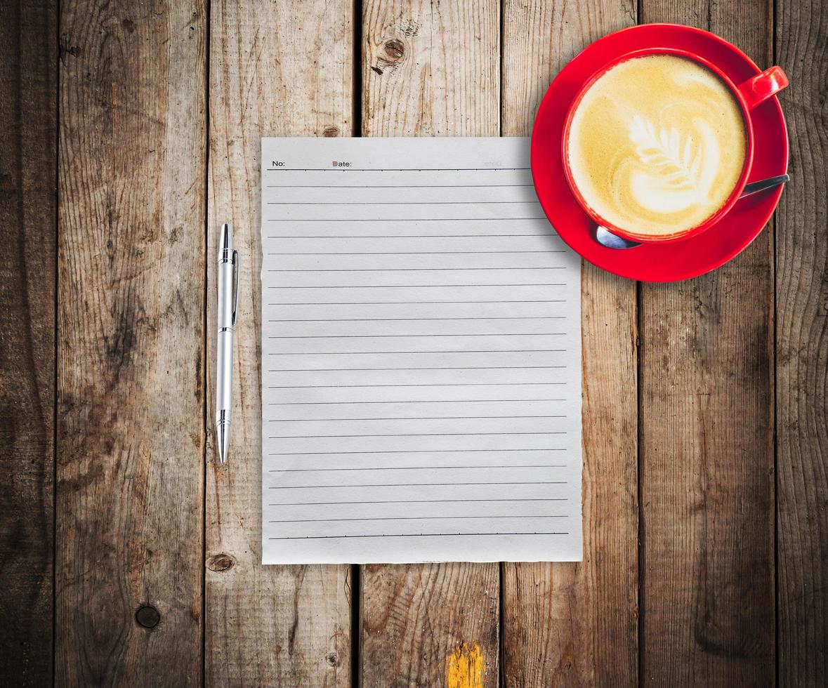 empty paper and pen with red cup coffee on wood table background photo